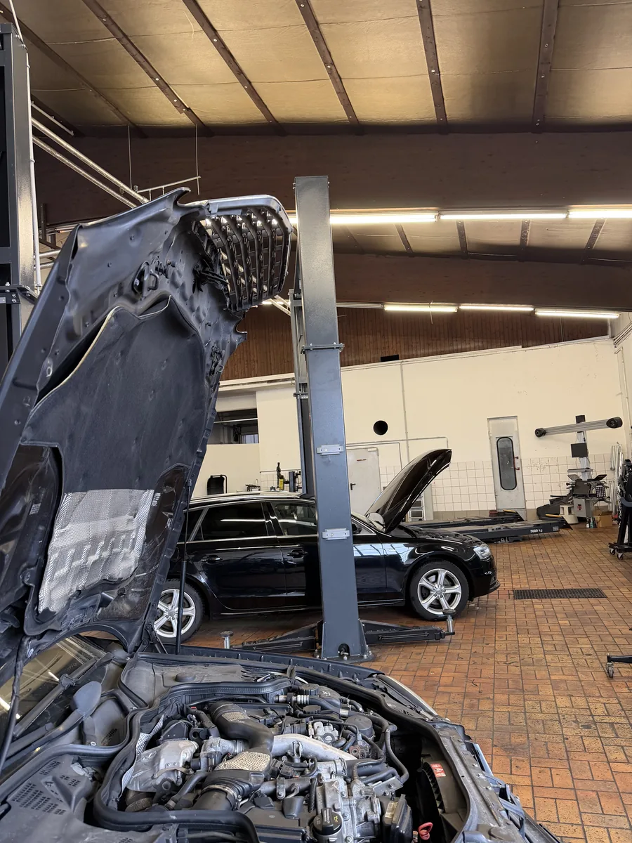 Mehrere Fahrzeuge mit geöffneten Motorhauben bei Reparaturarbeiten